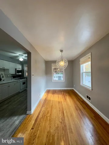 a view of a room with kitchen appliances and wooden floor
