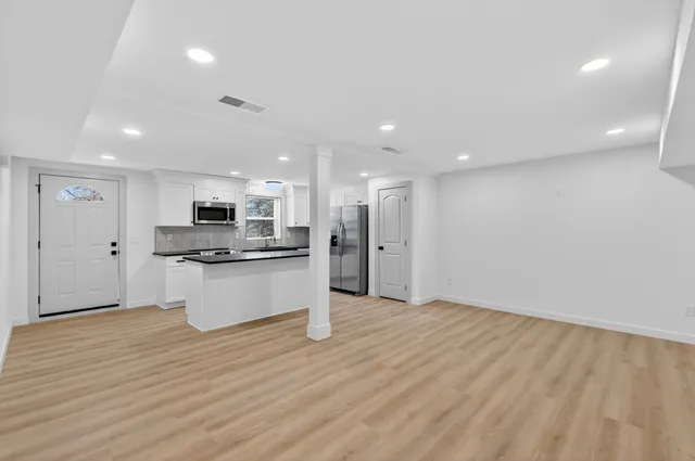 a view of kitchen with granite countertop refrigerator oven a sink and white cabinets with wooden floor