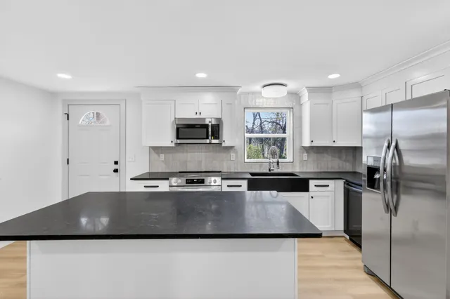 a kitchen with stainless steel appliances granite countertop a stove a sink and a refrigerator