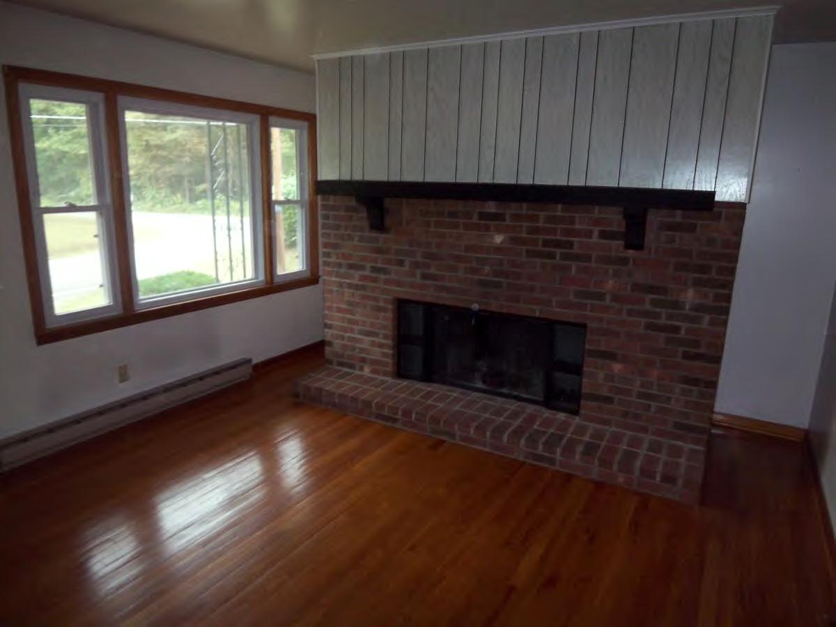 2610 The Great Road Fieldale, VA 24089 - Photo 2 of 9 an empty room with wooden floor a fireplace and windows
