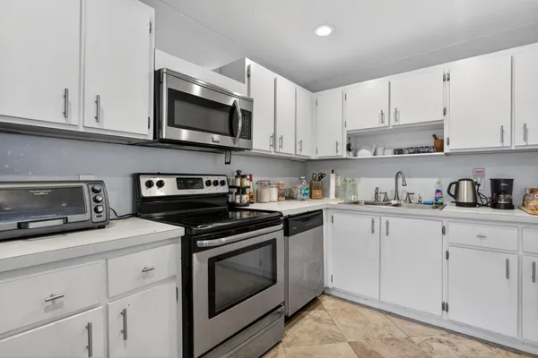 a kitchen with stainless steel appliances granite countertop grey cabinets a stove a sink and dishwasher