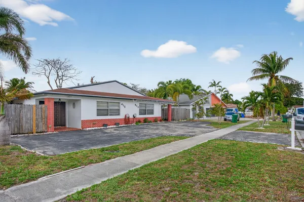 a front view of a house with a yard and potted plants
