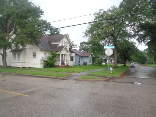 a view of a house with a yard and large trees