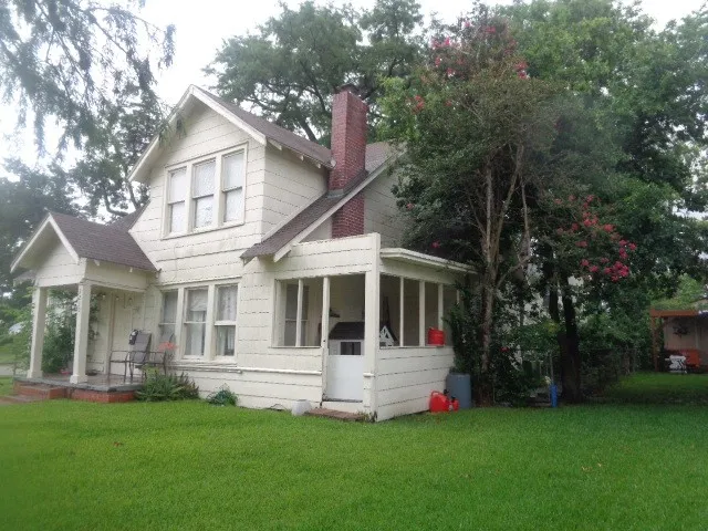 a view of house with yard and large trees