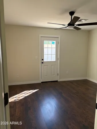 an empty room with wooden floor closet and windows