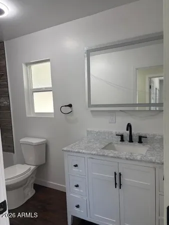 a bathroom with a granite countertop toilet sink and mirror