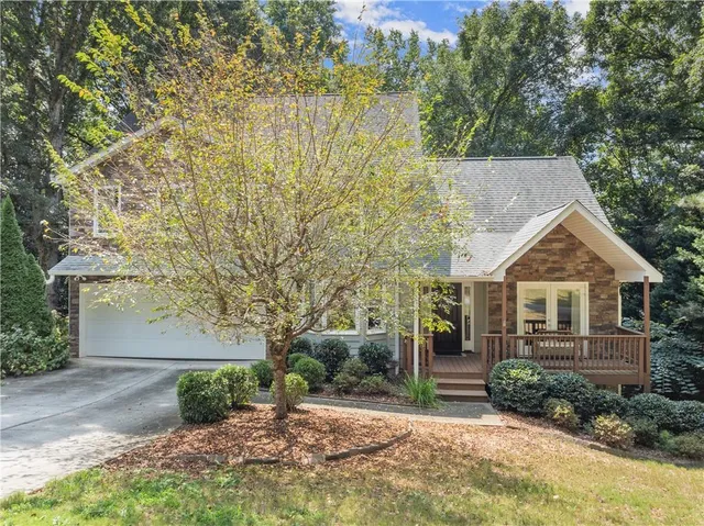 a view of a house with brick walls plants and large tree