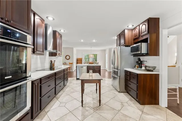 a kitchen with stainless steel appliances kitchen island granite countertop a stove refrigerator and sink