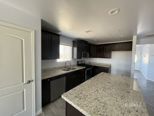 1224 South McCall Street Ridgecrest, CA 93555 - Photo 3 of 9 a kitchen with stainless steel appliances granite countertop sink stove and refrigerator