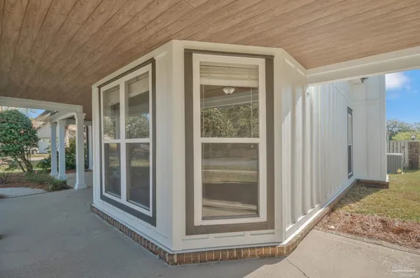 an empty room with wooden floor cabinet and windows