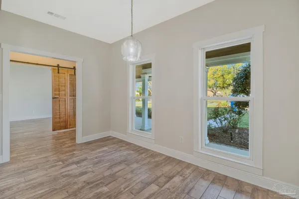 an empty room with wooden floor fan and windows