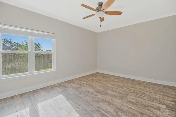 an empty room with wooden floor closet and windows