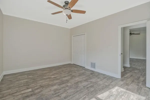 an empty room with wooden floor and ceiling fan
