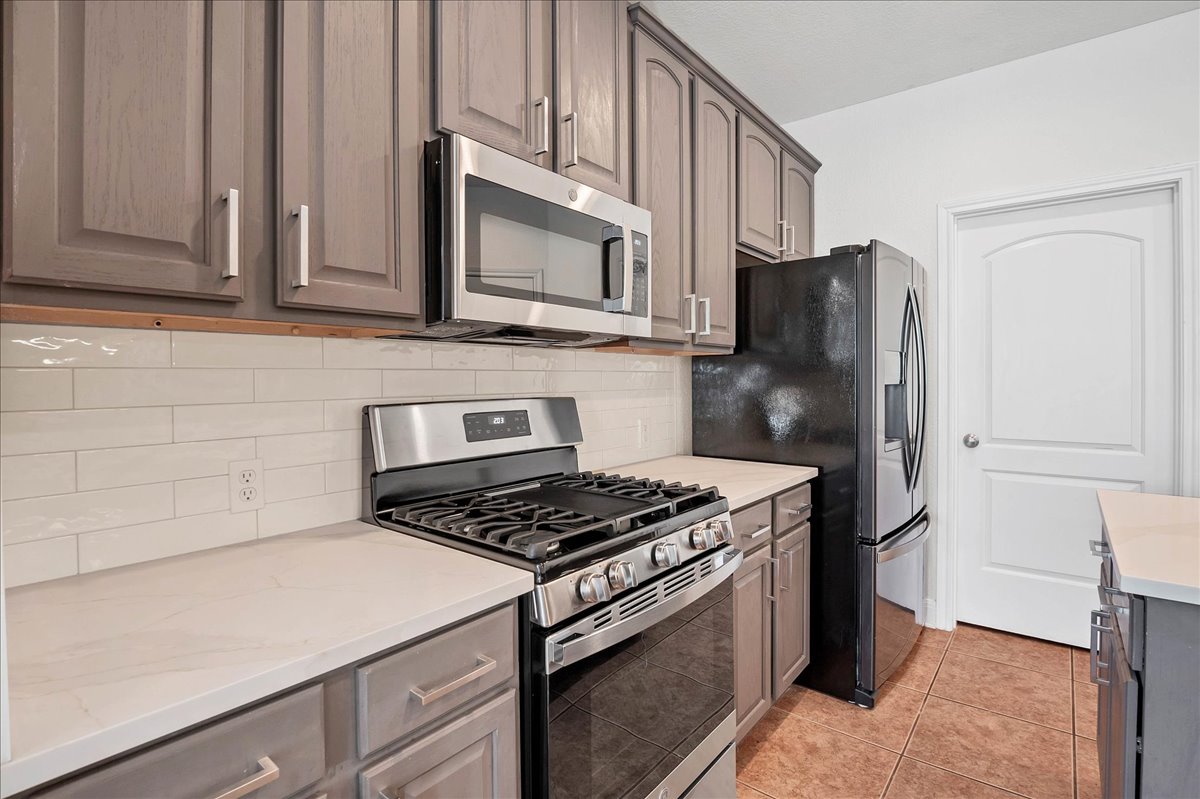 114 Aria Ridge, Unit 802 Lakeway, TX 78738 - Photo 10 of 30 a kitchen with stainless steel appliances granite countertop white cabinets a stove a microwave and a refrigerator