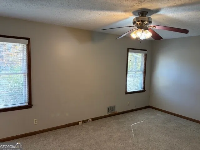 an empty room with windows and fan