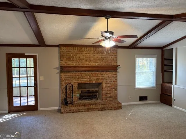 a view of an empty room with a fireplace and a window