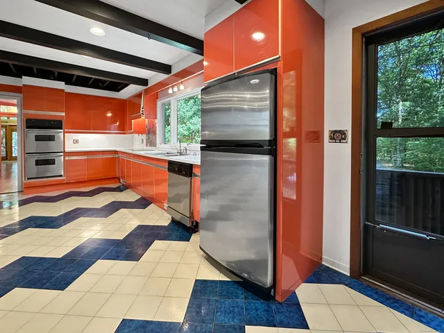 a kitchen with stainless steel appliances kitchen island granite countertop a refrigerator a sink and wooden floors