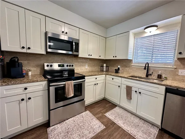 a kitchen with cabinets stainless steel appliances a sink and a window