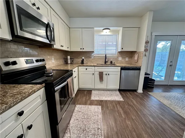 a kitchen with stainless steel appliances granite countertop a stove a sink and a microwave