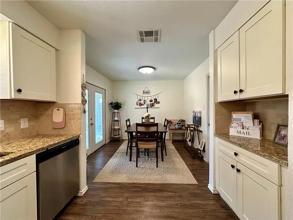 a kitchen with granite countertop a white cabinets and wooden floor