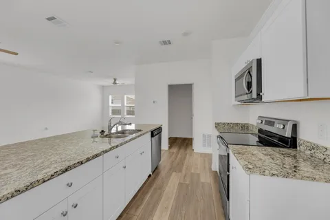 a kitchen with granite countertop a sink a stove and cabinets