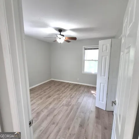 an empty room with wooden floor ceiling fan and windows
