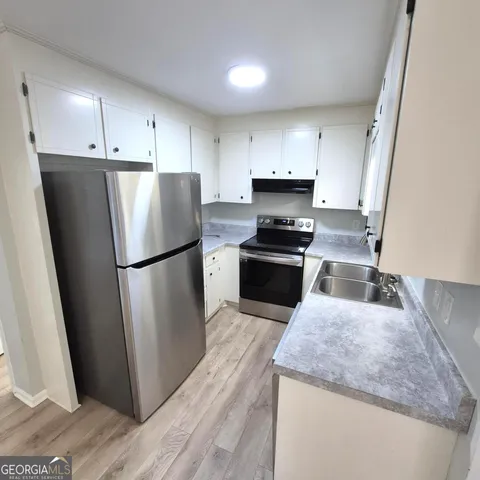 a kitchen with stainless steel appliances granite countertop a stove a refrigerator a sink a refrigerator and white cabinets