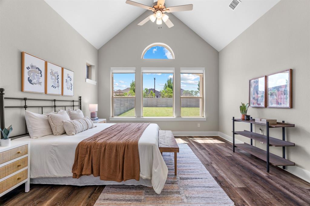 1821 Stonewall Road Argyle, TX 76226 - Photo 17 of 40 Vaulted ceiling with a ceiling fan, three large rear-facing windows, arched transom window, wood-finish flooring, and light-toned wall paint