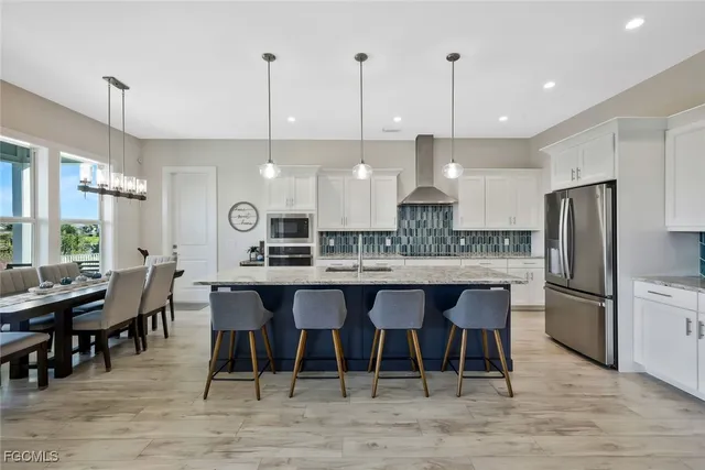 a kitchen with stainless steel appliances granite countertop a stove a refrigerator a kitchen island a dining table and chairs