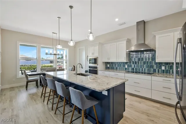 a large kitchen with stainless steel appliances a stove center island a oven a dining table and chairs