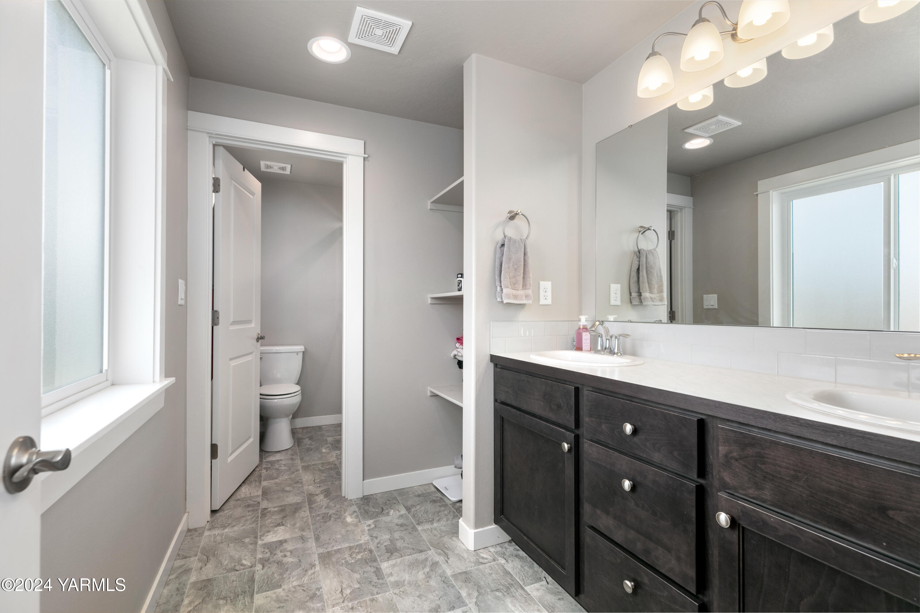 6210 Cottonwood Road Yakima, WA 98903 - Photo 10 of 18 a spacious bathroom with a double vanity sink a toilet and a mirror