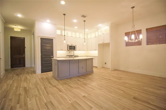a kitchen with stainless steel appliances granite countertop a sink a refrigerator and a wooden floor