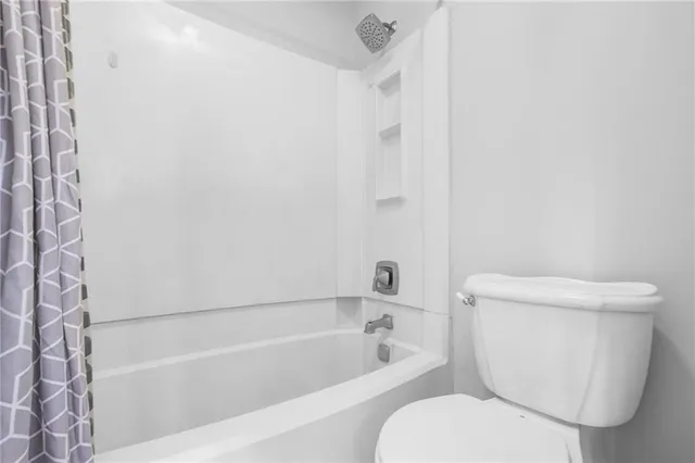 a white toilet sitting next to a bath tub