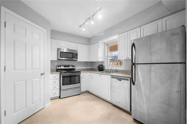 a kitchen with stainless steel appliances granite countertop a refrigerator a stove a sink and a microwave