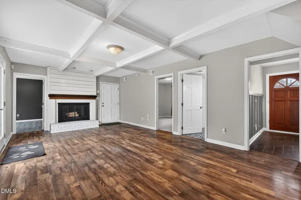 a view of an empty room with wooden floor fireplace and a window