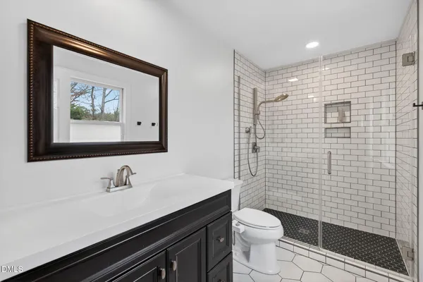 a bathroom with a toilet a sink a mirror and shower