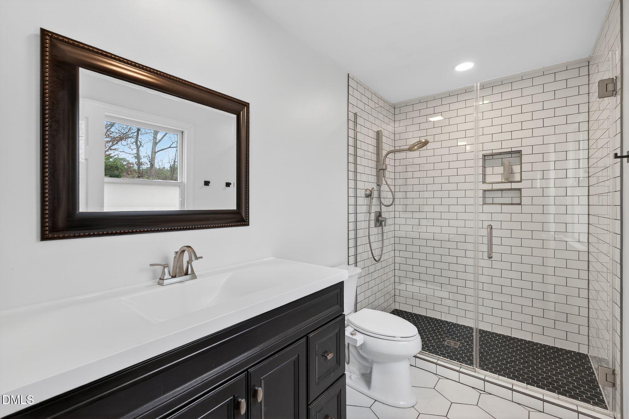 1201 Chardon Court Raleigh, NC 27609 - Photo 17 of 47 a bathroom with a toilet a sink a mirror and shower