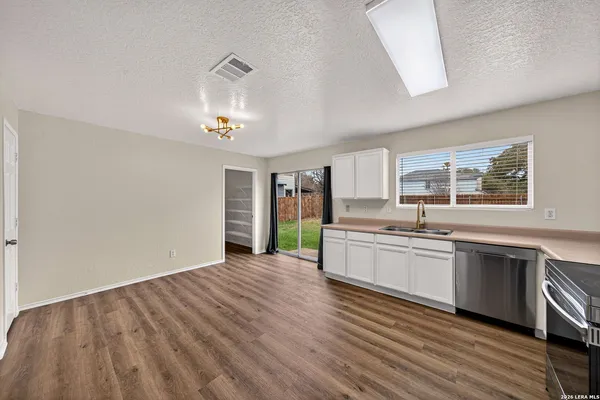 a kitchen with granite countertop a stove a sink and white cabinets with wooden floor