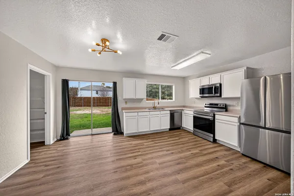 a kitchen with stainless steel appliances granite countertop a refrigerator a stove a sink dishwasher a oven with white cabinets and wooden floor