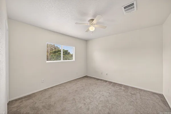 an empty room with a window and ceiling fan