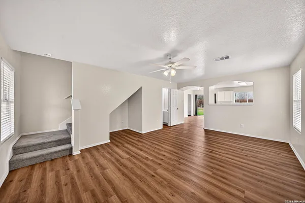 a view of empty room with wooden floor and fan