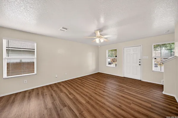 a view of an empty room with wooden floor and a window