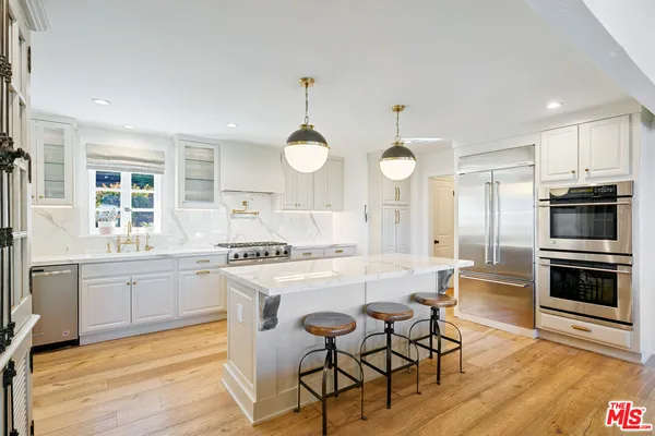 a large kitchen with kitchen island a large island in the center and stainless steel appliances