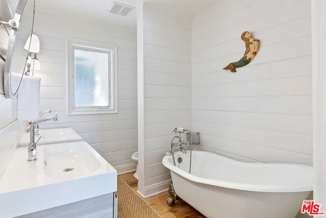 a white bath tub sitting next to a white sink and vanity
