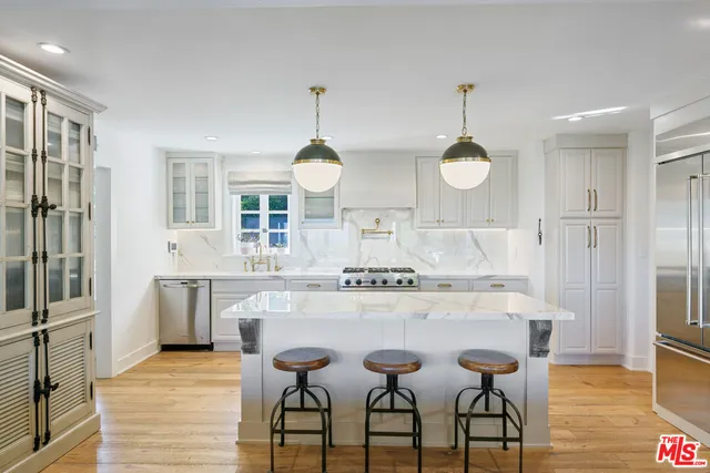 a kitchen with kitchen island granite countertop a stove a sink a dining table and chairs with wooden floor