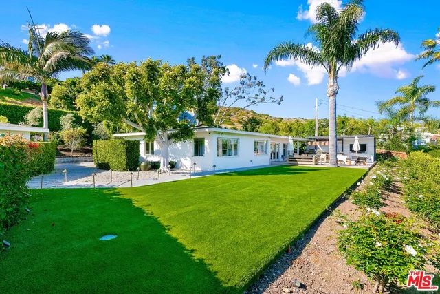 a view of a house with a big yard and palm trees