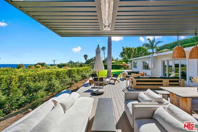 a view of a patio with couches table and chairs with wooden floor and fence