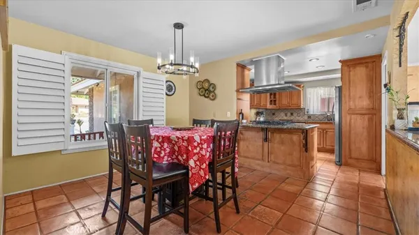 a kitchen with stainless steel appliances kitchen island granite countertop a table chairs in it and a window