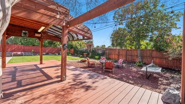 a view of a patio with table and chairs under an umbrella with a barbeque
