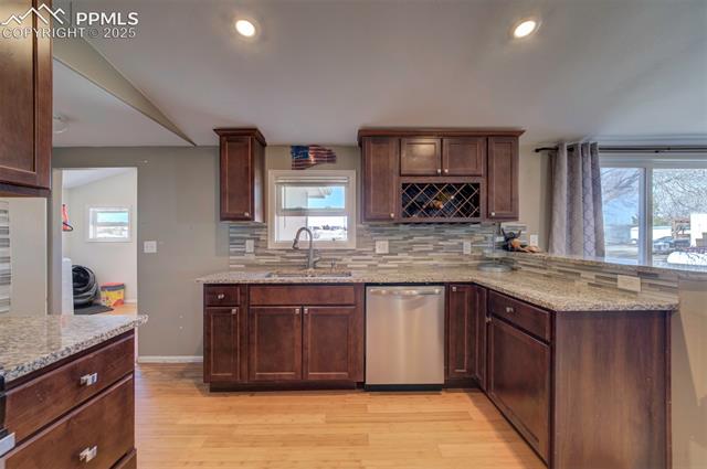 5860 Curtis Road Peyton, CO 80831 - Photo 16 of 28 Kitchen featuring a peninsula, light wood-style flooring, a sink, dishwasher, and backsplash